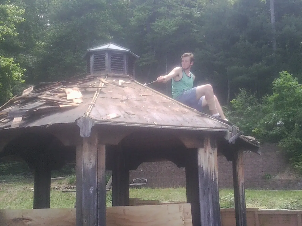 Tearing the old roof off a wooden gazebo before new shakes in Magnolia